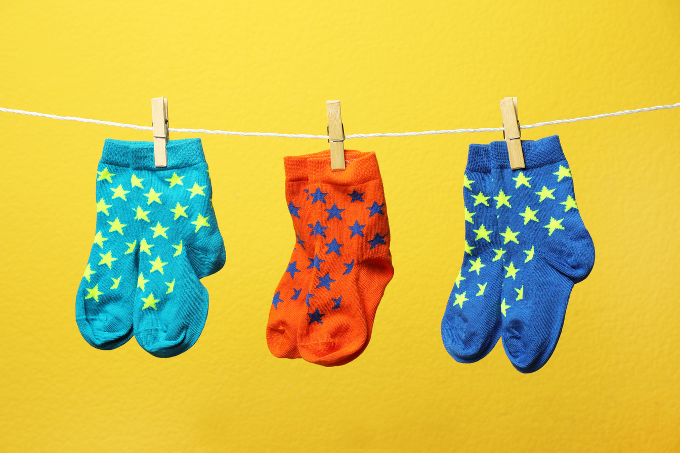 Different Socks on Laundry Line against Color Background
